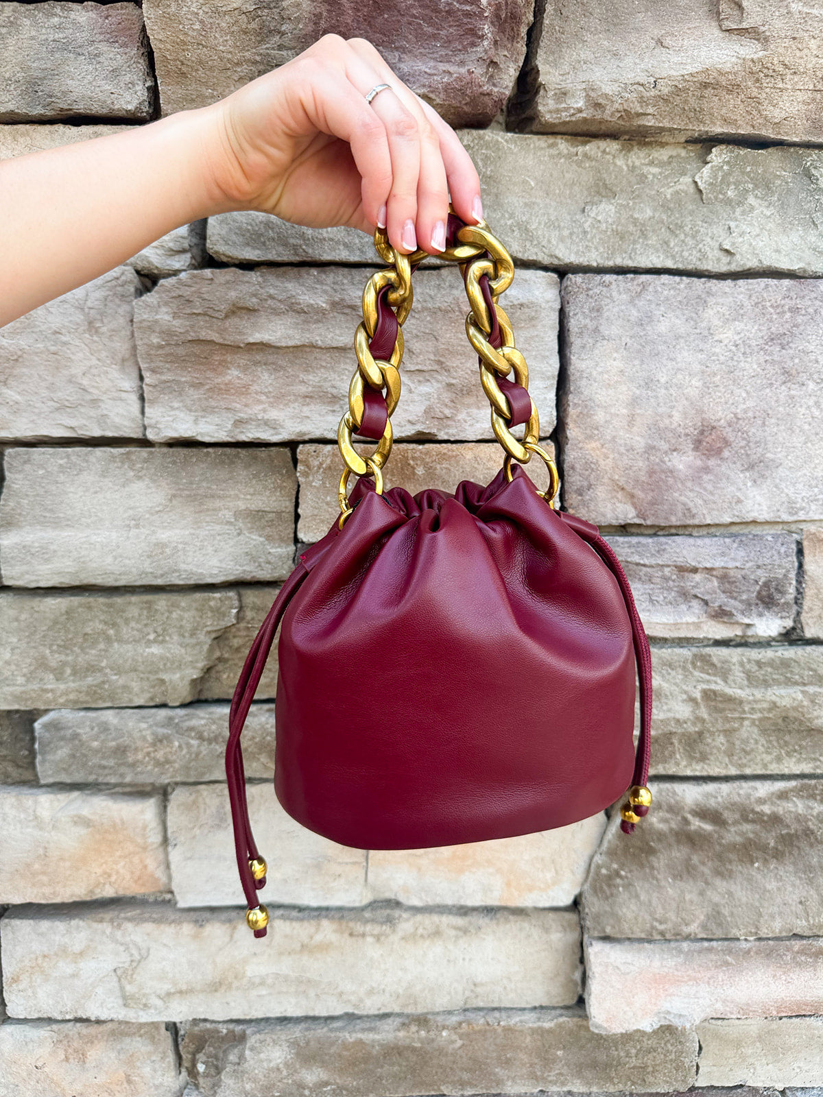 Garnet faux leather mini drawstring purse with chainlink handle woven with leather.