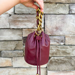 Garnet faux leather mini drawstring purse with chainlink handle woven with leather.