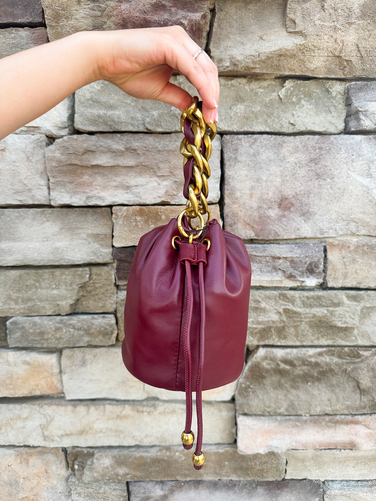 Garnet faux leather mini drawstring purse with chainlink handle woven with leather.