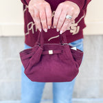 Modern structured mini tote bag with slouchy body, angular sides, top handles, and crossbody strap.
