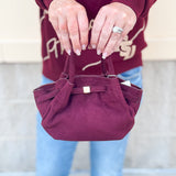 Modern structured mini tote bag with slouchy body, angular sides, top handles, and crossbody strap.