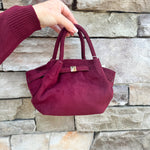 Modern structured mini tote bag with slouchy body, angular sides, top handles, and crossbody strap.