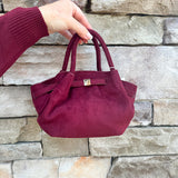 Modern structured mini tote bag with slouchy body, angular sides, top handles, and crossbody strap.