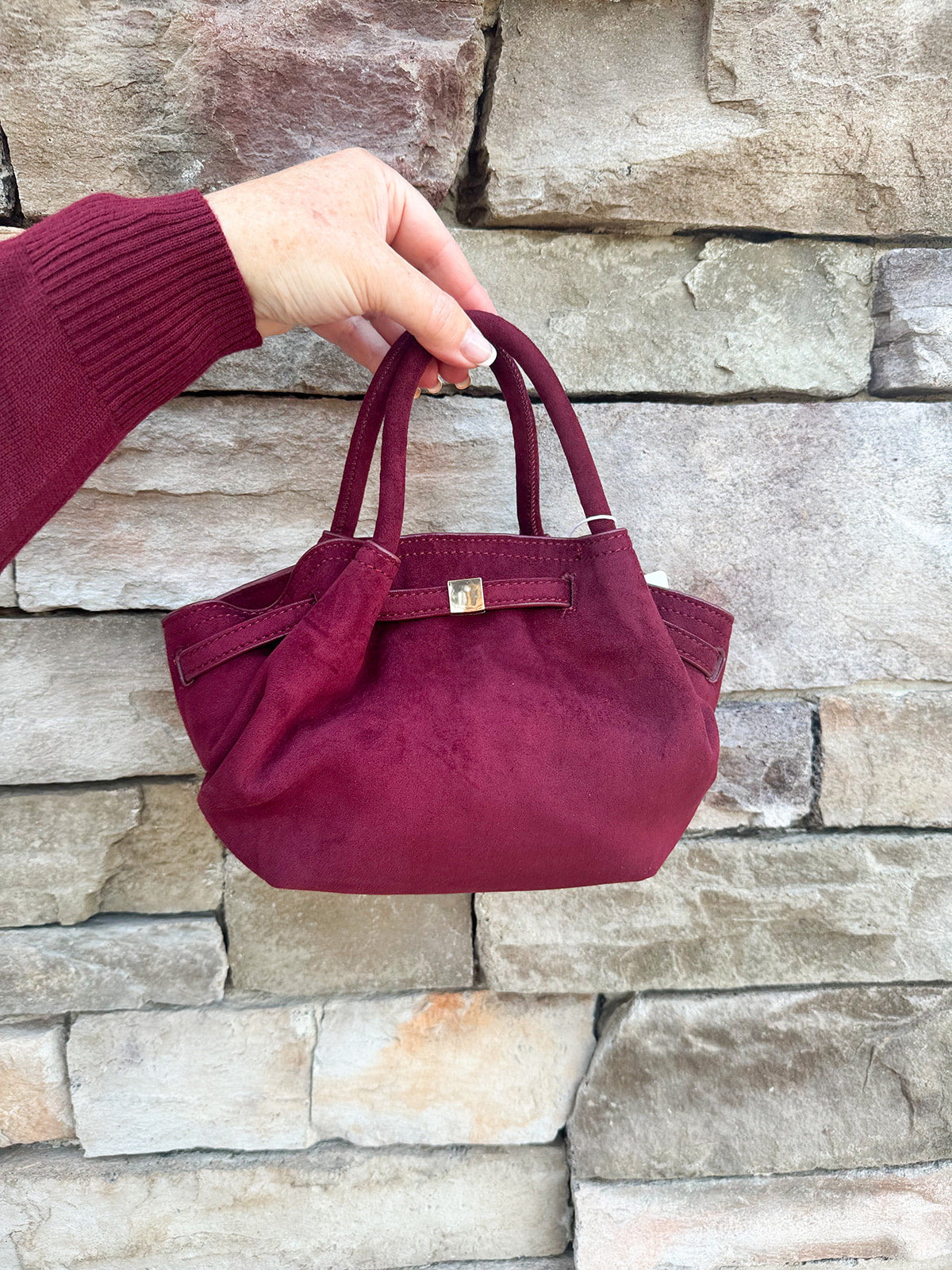 Modern structured mini tote bag with slouchy body, angular sides, top handles, and crossbody strap.