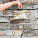 Clear stadium-approved bag with gold vegan leather accents, gold chain strap, and zipper.