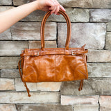 Structured caramel brown glossy faux leather tote with rounded handles and buckle accents.
