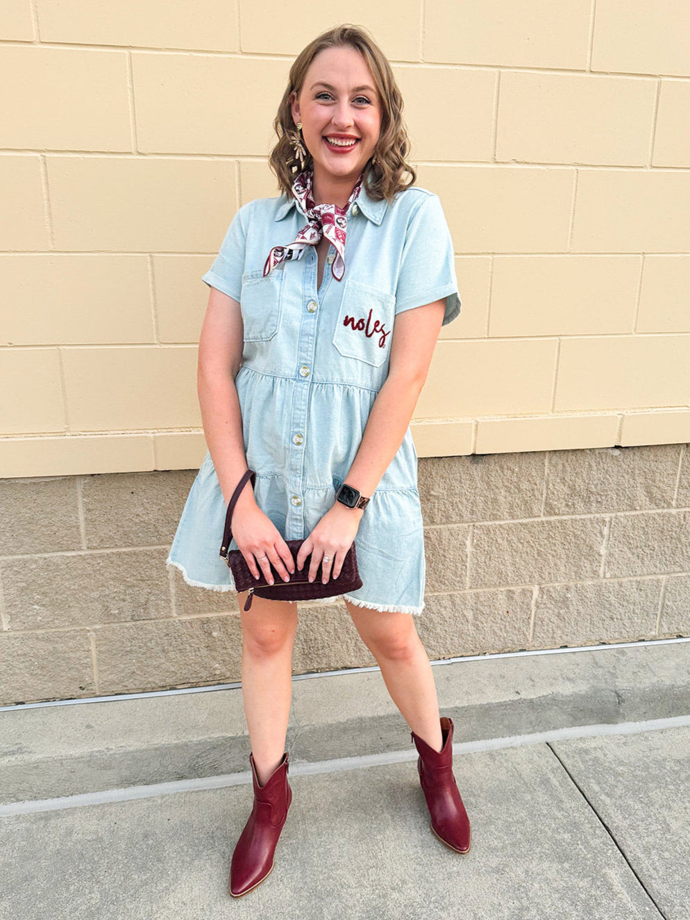 Light wash denim-style dress with cuff sleeves, V-neckline, raw hem, and embroidered garnet “Noles” script on pocket.