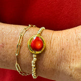 Gold beaded stretch bracelet with a raw red coral stone centered.