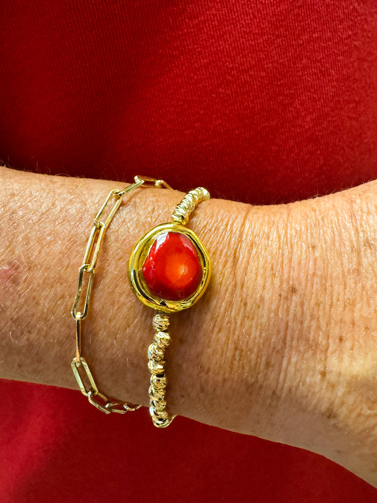 Gold beaded stretch bracelet with a raw red coral stone centered.