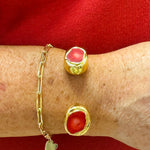 Gold cuff bracelet with raw red coral stones on each end.