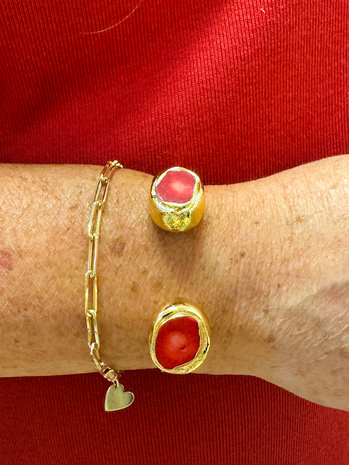 Gold cuff bracelet with raw red coral stones on each end.