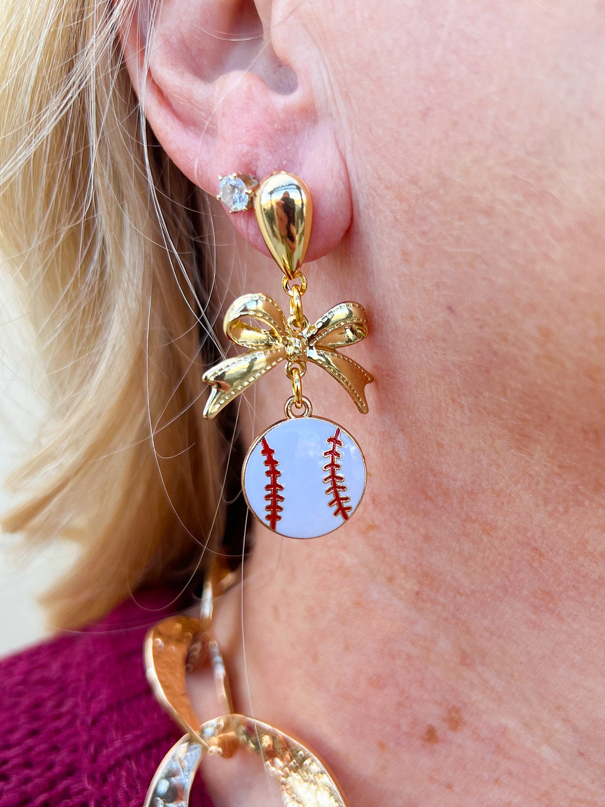 Gold dangle earrings with teardrop post, bow detail, and baseball charm