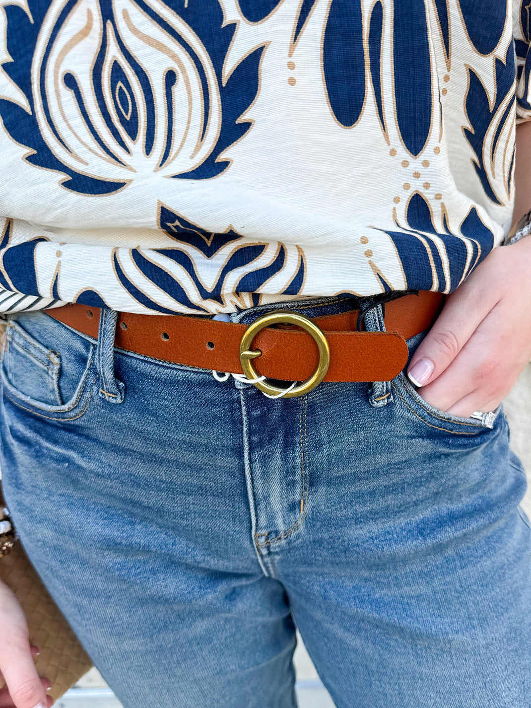 Tan leather belt with brass-toned circle buckle, available in multiple sizes.