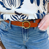 Tan leather belt with brass-toned circle buckle, available in multiple sizes.