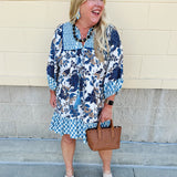 Mini dress with paisley-inspired print in soft blue, light orange, and cream, featuring tassel tie neckline and ¾ sleeves.