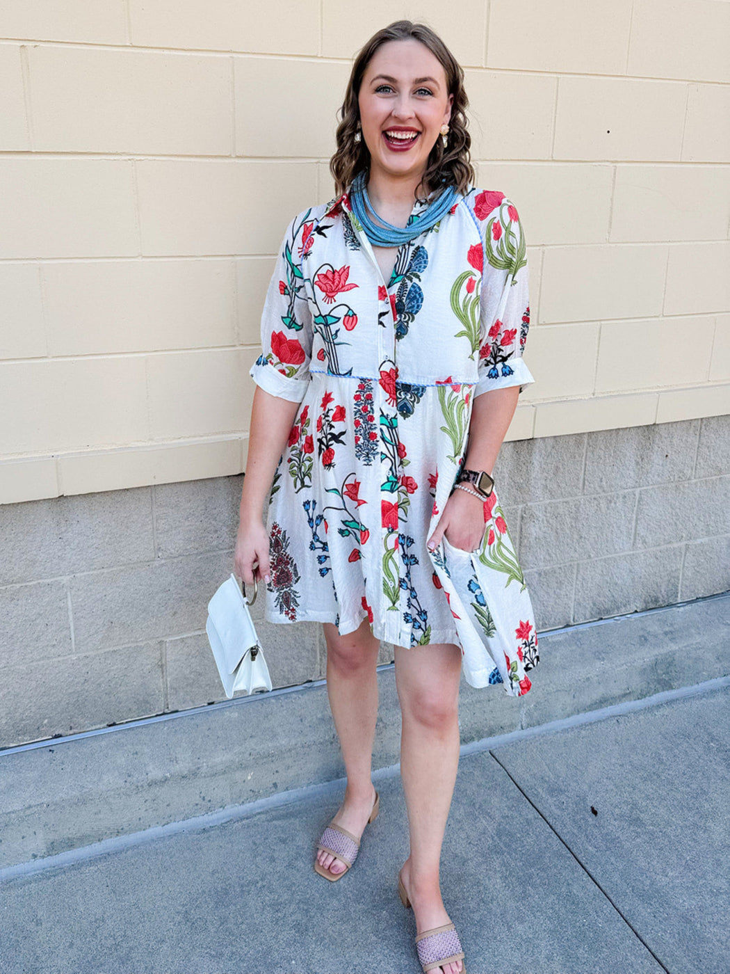 White mini shirt dress with button-down front, collar, ¾ sleeves, and striped piping details.
