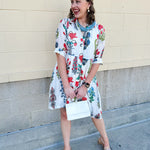 White mini shirt dress with button-down front, collar, ¾ sleeves, and striped piping details.