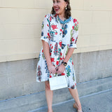 White mini shirt dress with button-down front, collar, ¾ sleeves, and striped piping details.