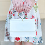 Joy Susan Aria Ring Bag in White displayed with a metallic ring handle, crisp vegan leather finish, and compact silhouette – styled as a wristlet, clutch, or crossbody for a versatile day-to-night look