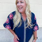 Navy puff sleeve top with ruffle neck and pink-orange floral embroidery
