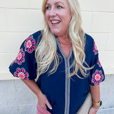 Navy puff sleeve top with ruffle neck and pink-orange floral embroidery