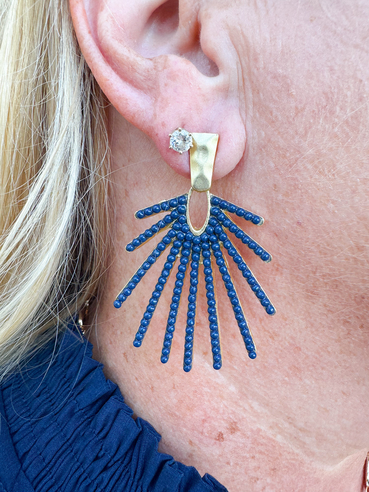 Navy statement drop earrings with a sunburst design, shown on a neutral background to highlight shine and shape