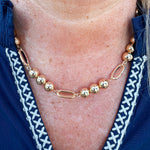 Gold beaded necklace with alternating round beads and open oval beads, adjustable length.
