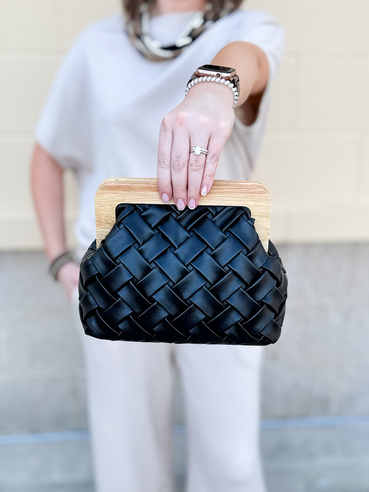 Black woven clutch with wood clasp and gold crossbody chain