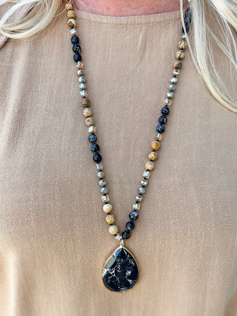 Black and tan beaded necklace with black marbled stone pendant.