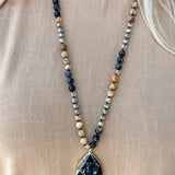 Black and tan beaded necklace with black marbled stone pendant.