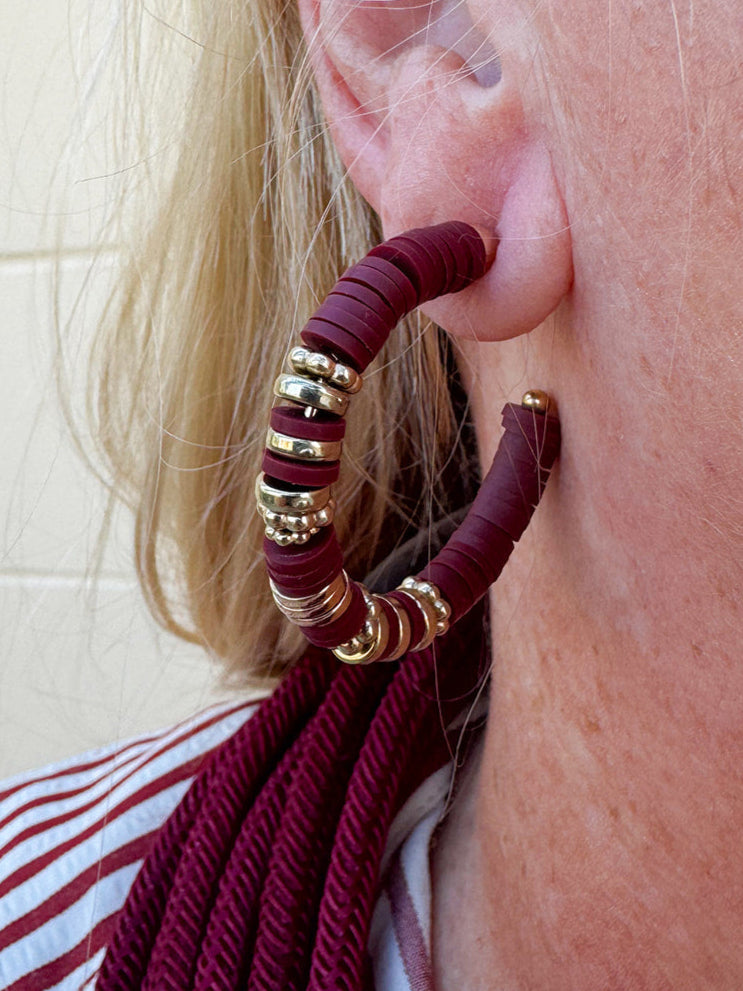 Hoop earrings with garnet rubber disks and gold metal accents, styled for fall, holiday, or gameday looks.