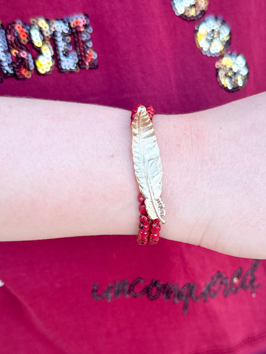 Two-stack bracelet set with garnet glass beads and gold metal feather charm
