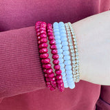 A seven-piece bracelet stack with white, diamond-style, and garnet beaded bracelets, styled for gameday or fall wear.