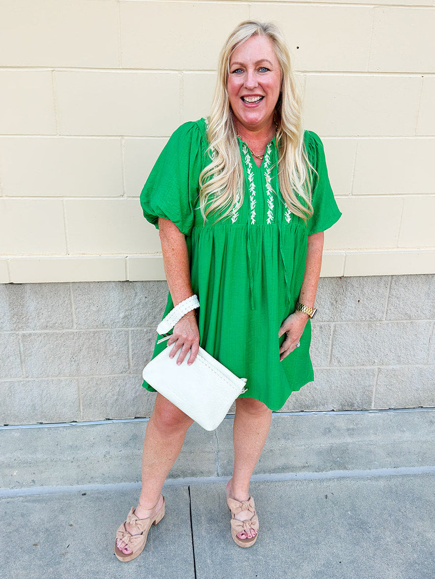 Kelly green embroidered babydoll dress with puff sleeves, tie neck, and side pockets—lightweight and perfect for warm weather