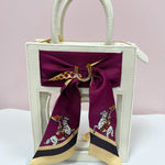 Clear crossbody bag with cream leather trim, gold hardware, and a removable team scarf.