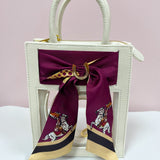 Clear crossbody bag with cream leather trim, gold hardware, and a removable team scarf.
