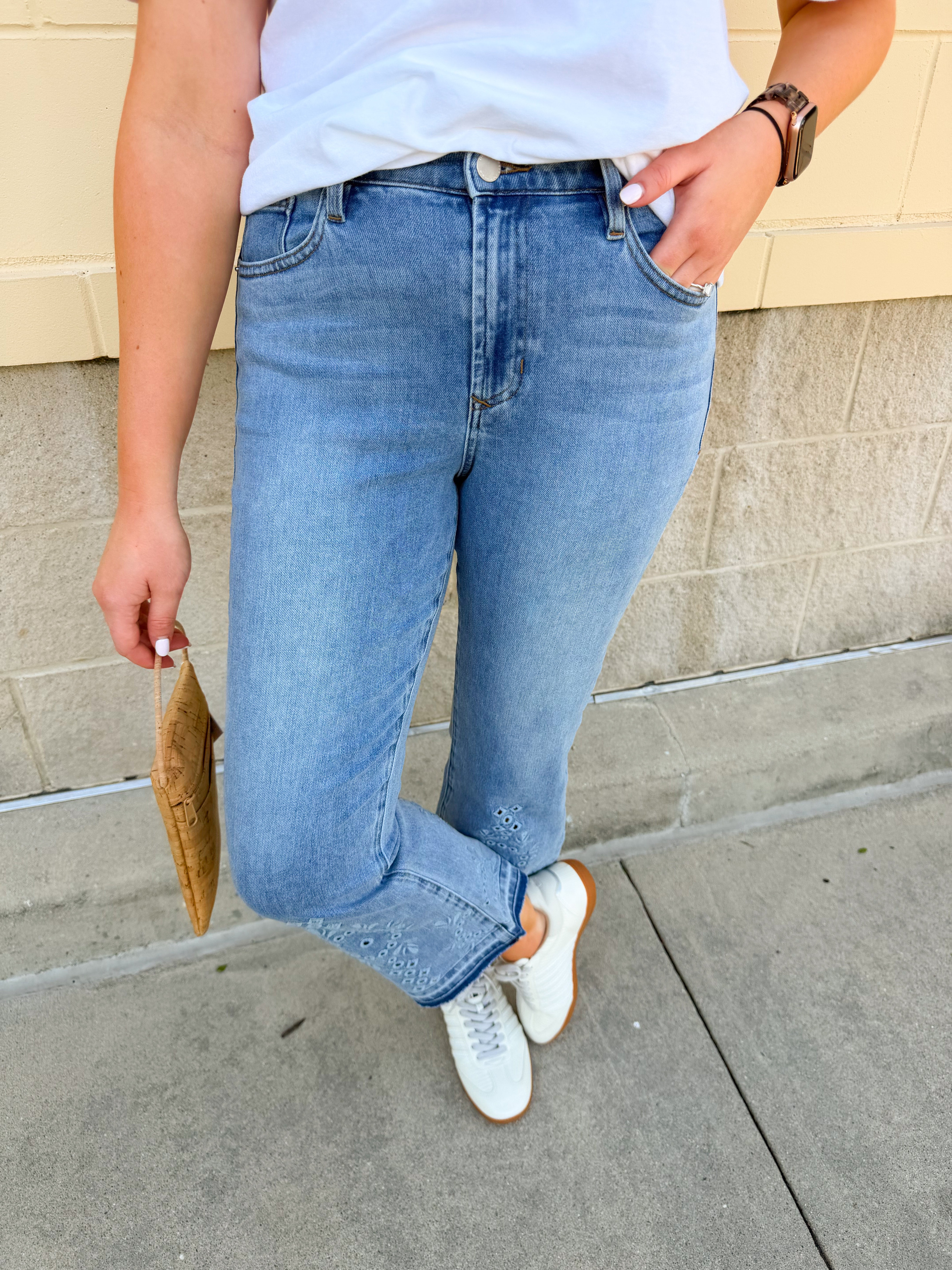 Light wash cropped flare jeans with embroidered eyelet detailing at the hem, classic five-pocket styling, and a flattering fitted silhouette through the hips and thighs.