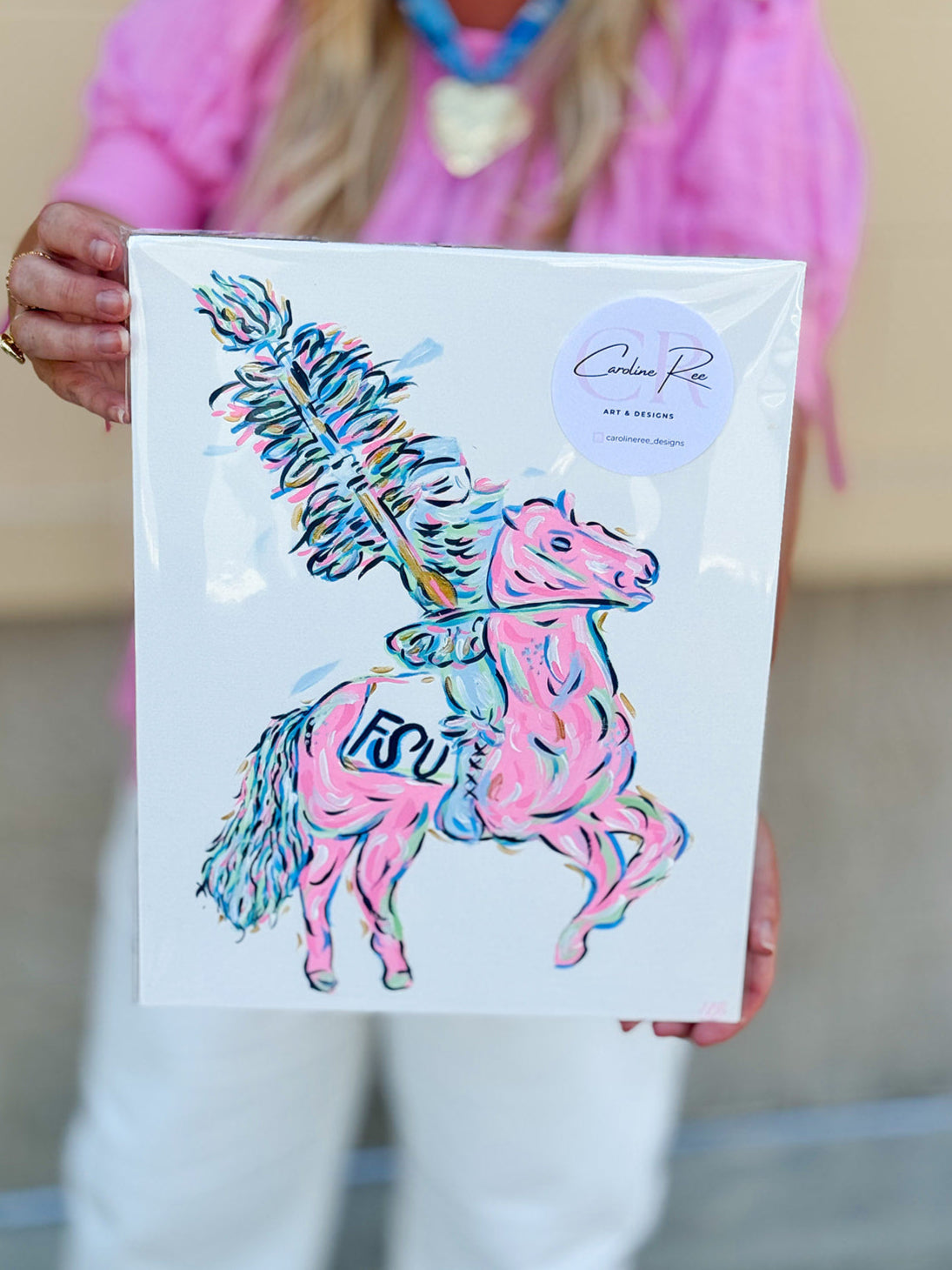 A bold, colorful canvas featuring a stylized hand-painted rendition of the FSU Renegade mascot in pink, gold, and blue tones on an 11"x14" canvas.