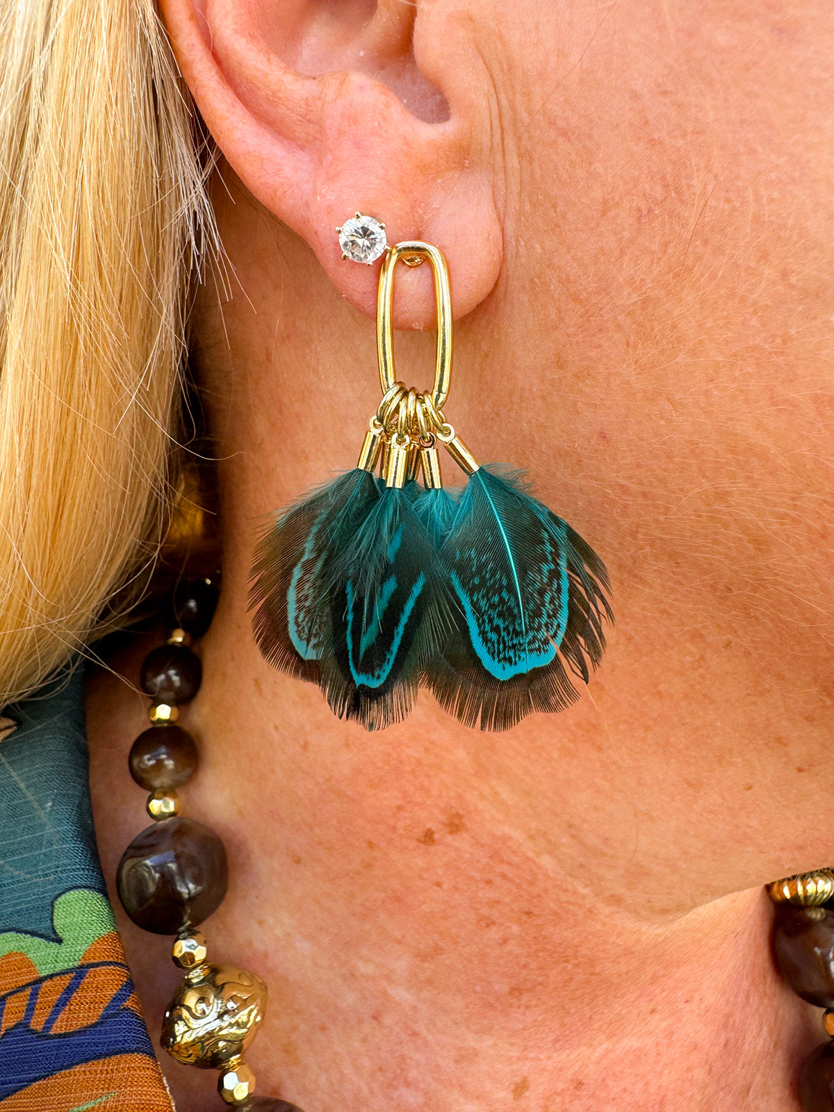 Peacock-patterned feather tassel earrings in blue and grey, approximately 2.5 inches long.