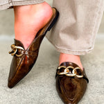 Bronze slip-on mules with glossy finish, gold chain detail, and pointed toe.