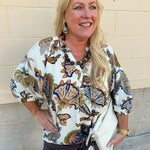 Cream floral top with navy, green, blue, and tan oversized print and V-neck with buttons