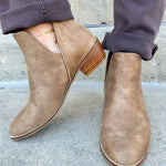 Taupe faux leather ankle booties with side cutouts, back zipper, and block heel.