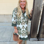 Olive and cream printed mini dress with collared V-neckline, button detailing, ¾ sleeves, and flowy A-line fit.