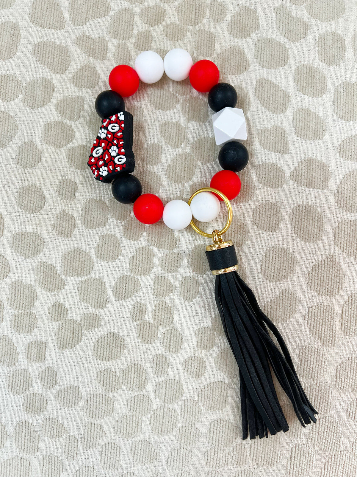 Round silicone beaded keychain with red, black, and white beads, tassel, and UGA charm