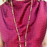 Long gold beaded necklace with alternating round beads and open oval beads, 34" length.