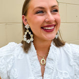 Oversized glittery earrings with a creamy base and swirls of gold and silver, styled for a bold and playful celestial look.