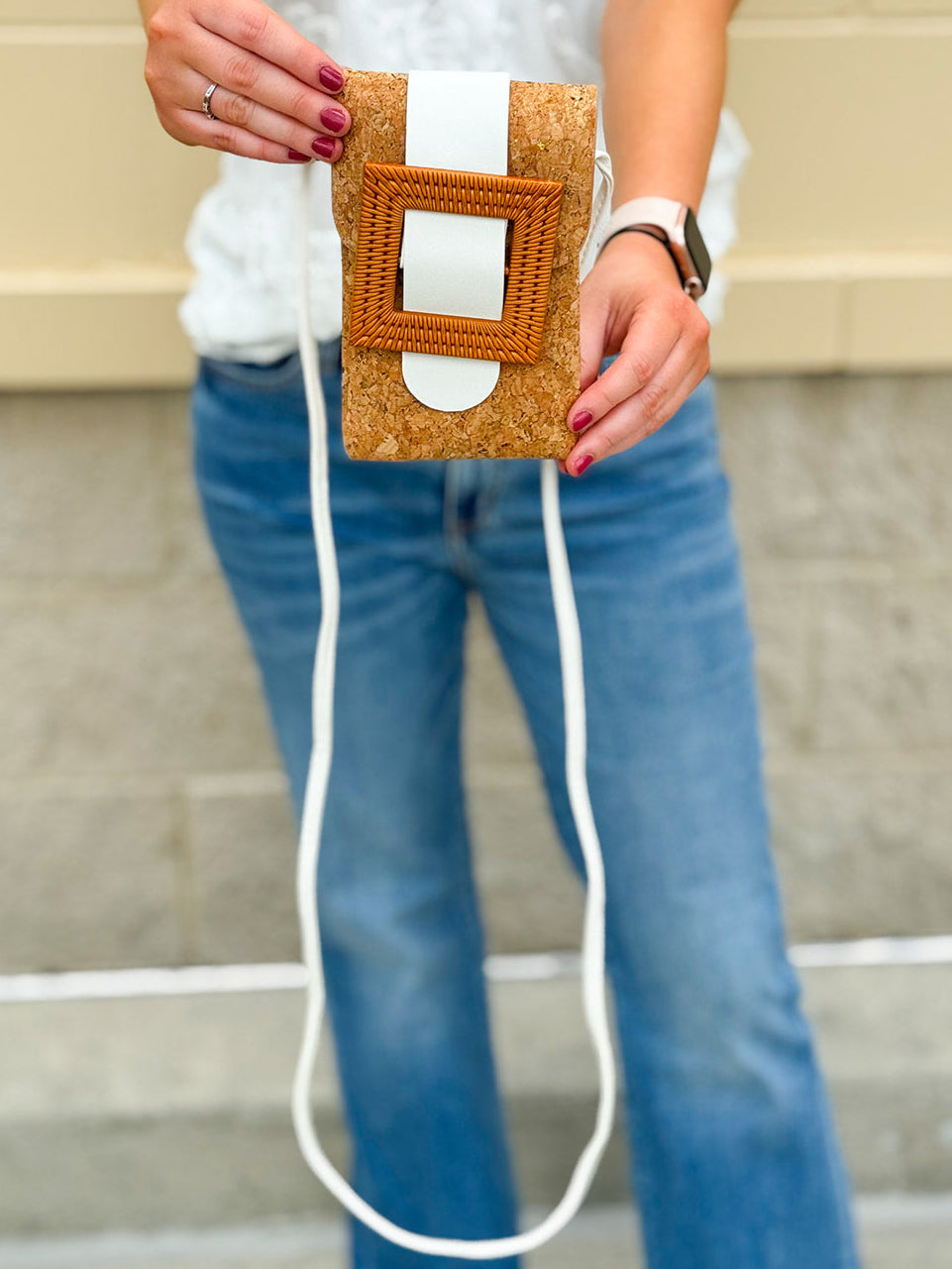 White eco-friendly cork crossbody bag with sleek design and adjustable strap, styled for casual and polished everyday looks.