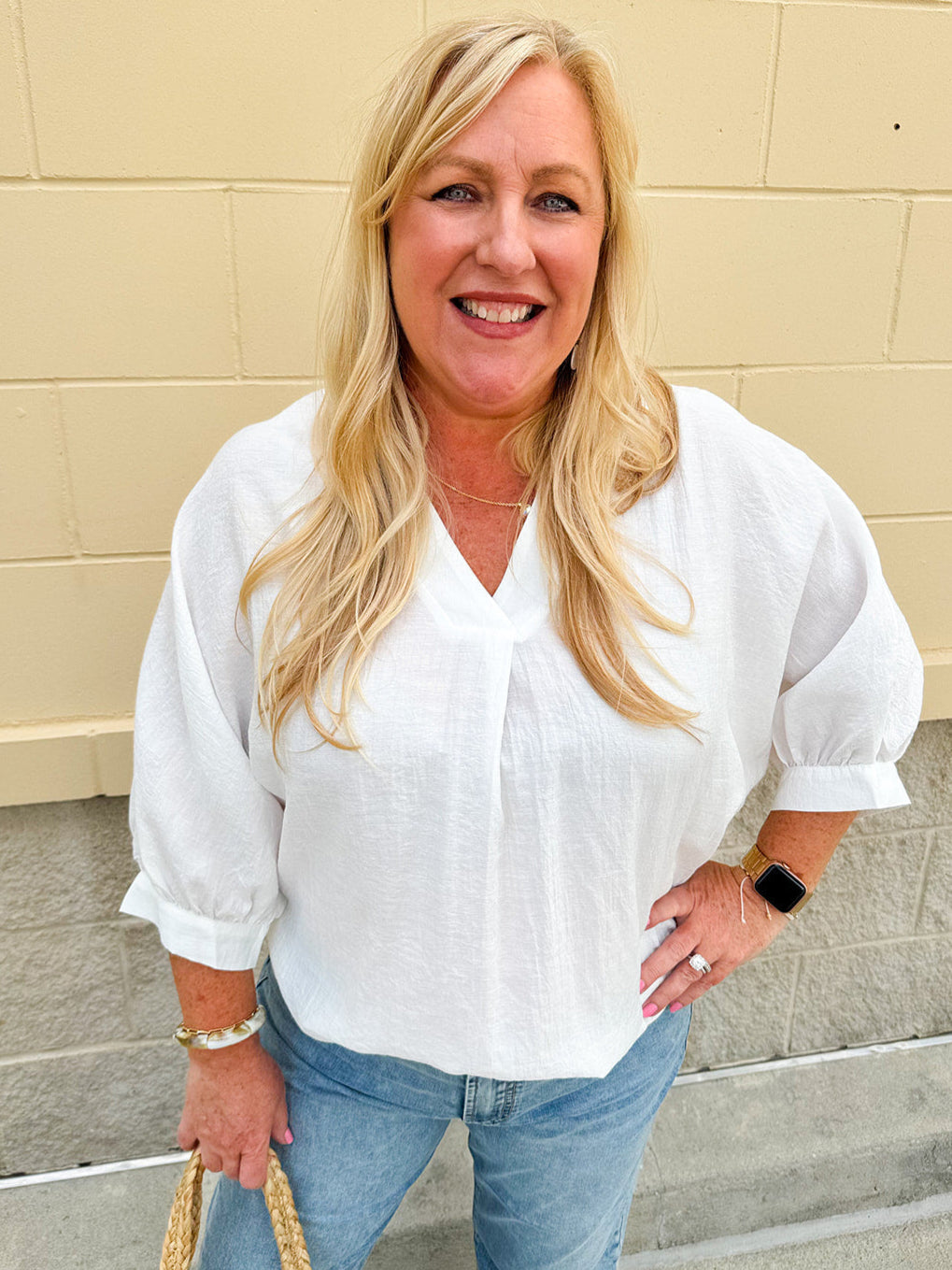 White V-neck loose-fit blouse with pleated cuffed sleeves, styled for a clean and classic outfit.