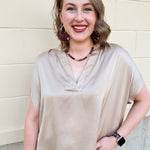 Gold silky blouse with split V-neckline, cuffed short sleeves, and relaxed drape