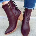 Garnet faux leather pointed toe ankle boot with stacked heel, inner side zipper, and lace-up back detail.